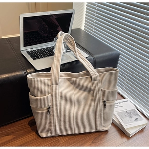 Beige corduroy tote bag detail with side zipper on a black chair with a laptop