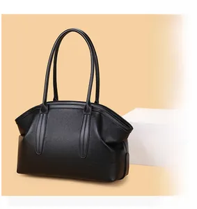 Detail of black pebbled leather texture on a minimalist shell-shaped tote bag