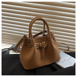Detail of brown suede bucket bag featuring white stitching and gold buckle hardware
