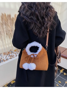Detail of a brown suede bucket bag with white faux fur trim and cute fuzzy pom-pom tassels