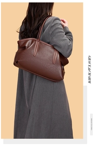 Detail view of large dark brown leather tote bag with soft pebble texture and shoulder strap