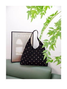 Detail of black suede hobo bag with golden metal eyelets and large capacity design