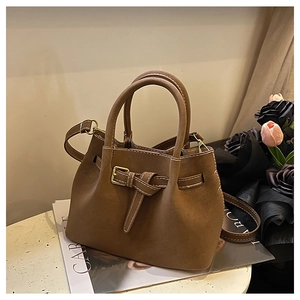 Brown frosted leather bucket bag with decorative buckle on a table setting