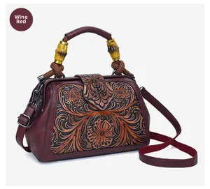 Detail of wine red leather handbag featuring floral embossing and bamboo handle