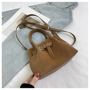 Close-up of brown suede bucket bag with white contrast stitching and metal buckle strap