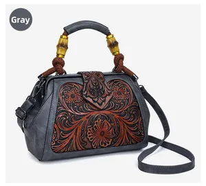 Close-up of vintage grey handbag featuring floral embossing and bamboo wood handles