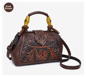 Detail of dark brown retro leather bag with embossed floral pattern and bamboo handle