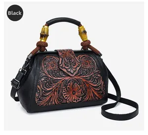 Detail of retro black leather handbag with copper floral embossing and bamboo wood handle