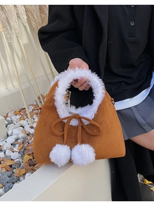 Detail of winter brown suede bucket bag with plush faux fur lining and white fur ball charms