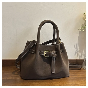 Detailed close-up of dark brown suede bucket bag featuring contrast stitching and buckle