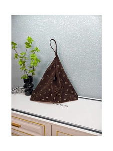 Macro shot of dark brown suede pyramid tote featuring elegant golden metal eyelets detail