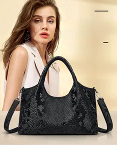 Detail of black snakeskin embossed handbag with silver metal hardware and detachable strap