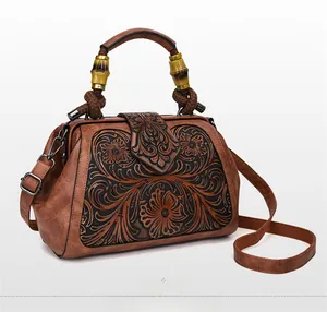 Detail view of vintage brown leather bag with floral embossing and decorative bamboo handle