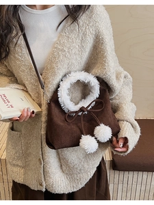 Detail of vintage brown suede bucket bag featuring plush white faux fur trim and soft pom-poms