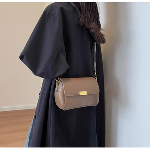 Detail of vintage brown crossbody bag with gold buckle on model with black coat