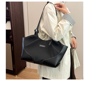 Detail of a black nylon tote bag with white contrast stitching and long shoulder straps