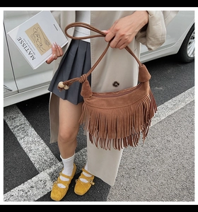 Detail of bohemian brown suede hobo bag with long tassels and wooden bead accents