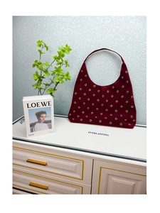 Detail of burgundy hobo shoulder bag with golden metallic eyelets and suede texture