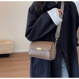 Detail of lychee pattern leather crossbody bag with ethnic style wide strap and gold buckle