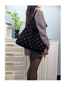 Detail shot of a black hobo bag with gold metal eyelets and large suede capacity