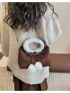 Detail showing plush white faux fur trim and cute soft pom poms on a brown bucket bag