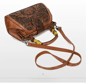 Close-up of retro leather bag featuring floral embossing and natural bamboo handle