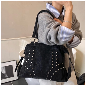 Detail of vintage tote bag featuring silver rivet studs and matte textured material