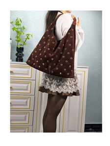 Detail of dark brown hobo bag featuring decorative golden metal grommets and rivets
