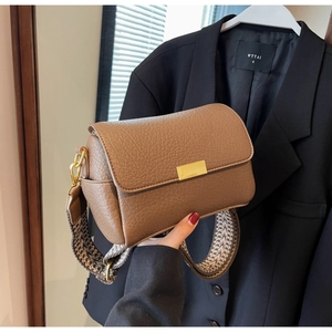 Detailed shot of brown litchi grain leather crossbody bag with geometric woven strap