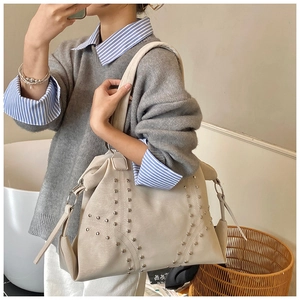 Detail of off-white tote bag with silver studs and soft leather texture for office commuting