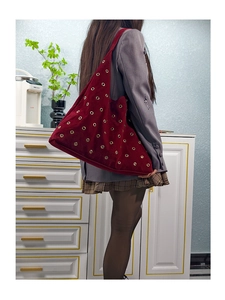 Detail of studded burgundy suede tote bag showing its large capacity on a model's shoulder