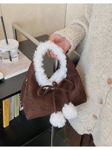 Detail of plush brown bucket bag featuring white faux fur handle and bow accent