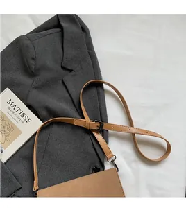 Detail of adjustable strap and black metal buckle on camel suede crossbody bag
