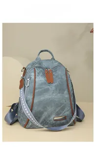 Detail of grey-blue canvas backpack with brown leather trim and woven geometric strap