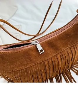 Close-up of brown suede hobo bag featuring fringe details and smooth silver metal zipper