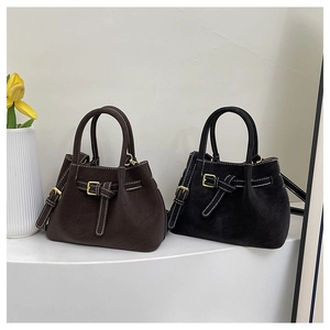 Detail of suede bucket bags with white stitching and decorative gold belt buckles