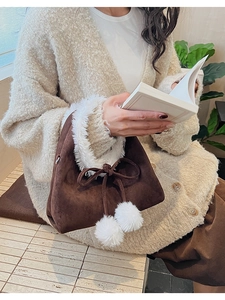 Detail of suede bucket bag with white faux fur trim and plush pom-pom bow detail