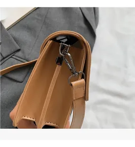 Macro detail of caramel leather crossbody bag with accordion folds and dark metal hardware