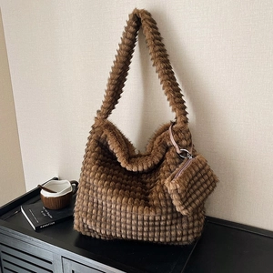 Brown faux fur cloud tote bag with quilted texture and matching coin purse on dark cabinet