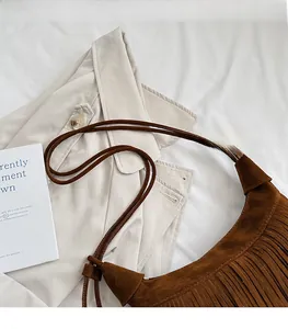 Detail of brown suede shoulder bag with long fringes and comfortable strap in retro style