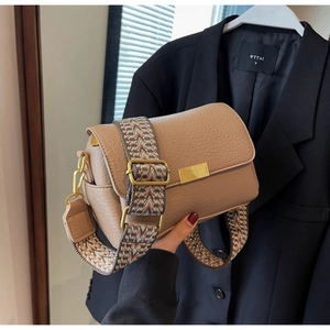 Detail of light brown pebble leather flap bag featuring wide geometric jacquard strap