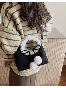 Detail of winter bucket bag with white faux fur trim, black ribbon bow, and plush balls