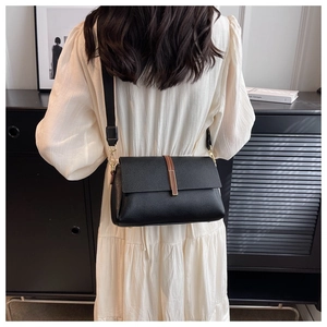 Close-up of black litchi texture crossbody bag with wide strap and metal hardware