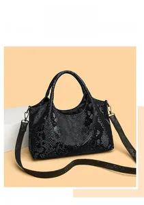 Detail of black snakeskin pattern leather handbag with dark hardware and adjustable strap