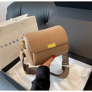 Close-up of khaki crossbody bag with wide jacquard strap in premium gift packaging