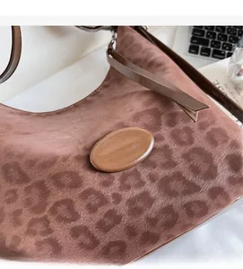 Detail of leopard print shoulder bag with satin texture and brown leather patch
