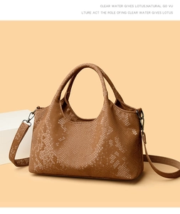Close-up of brown snake-embossed leather texture and metallic buckle on handbag
