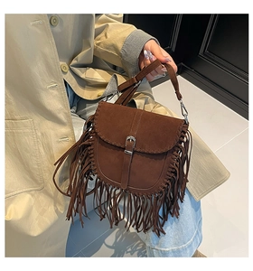 Détail d'un sac besace en daim marron foncé avec franges et boucle en métal argenté