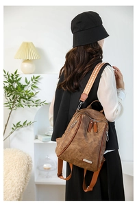 Detail of vintage brown leather backpack with patterned jacquard strap in cozy room