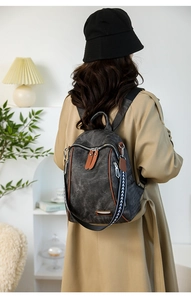 Detail of dark grey canvas backpack with brown leather trim and patterned shoulder strap